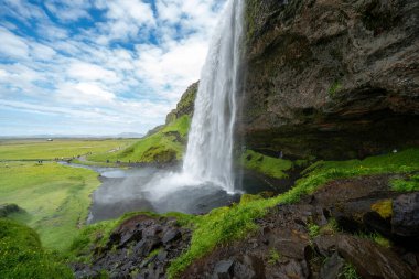 Seljalandsfoss şelalesi İzlanda 'da, şelalenin arka tarafına yaklaşıyor.