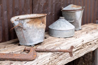 Paslı çivilerle ahşap bir masada duran eski paslı metal kova.