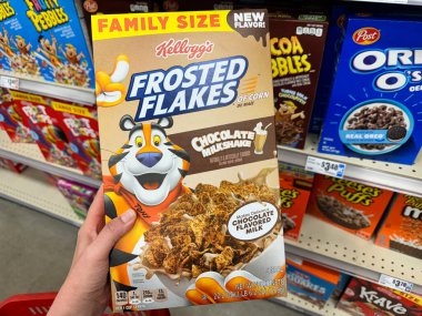 Temple, Texas - 26 Haziran 2024: Hand 'in elinde bir kutu Kelloggs Donmuş Flakes Çikolatalı Milkshake aromalı mısır gevreği var