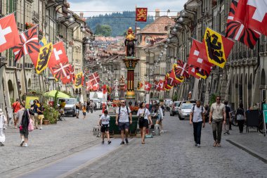 Bern, İsviçre - 22 Temmuz 2024: İsviçre 'nin Bayrakları, Bern Şehri ve Kantonu İsviçre' nin başkenti Bern 'in işlek ortaçağ kasabasının caddesinde sallanıyor