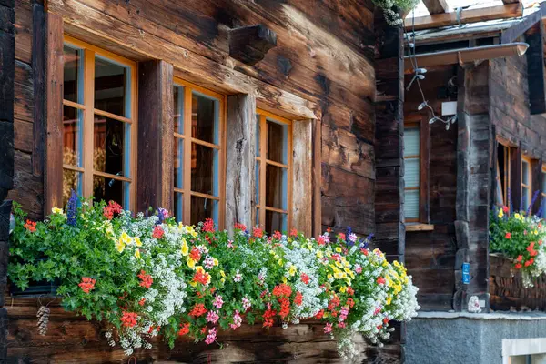 stock image Picturesque chalet window with red flowers in flower box in Zermatt, Switzerland, during summertime