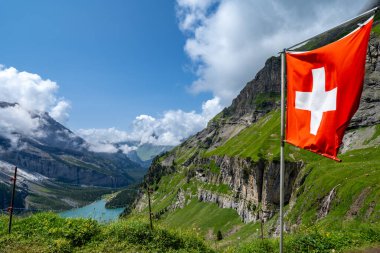 İsviçre 'de Oeschinensee Gölü boyunca yürüyüş yapan İsviçre Bayrağı