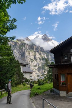 Murren,Switzerland - July 23, 2024: Hikers on the paved hiking trail from Murren to Gimmelwald village clipart