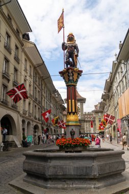 Bern, İsviçre - 22 Temmuz 2024: Zahringerbrunnen çeşmesinde, Bern 'in ana caddelerinden biri olan kalabalık Marktgasse' de bir bayrak taşıyan şehir kurucusu ve bir ayı görülüyor.