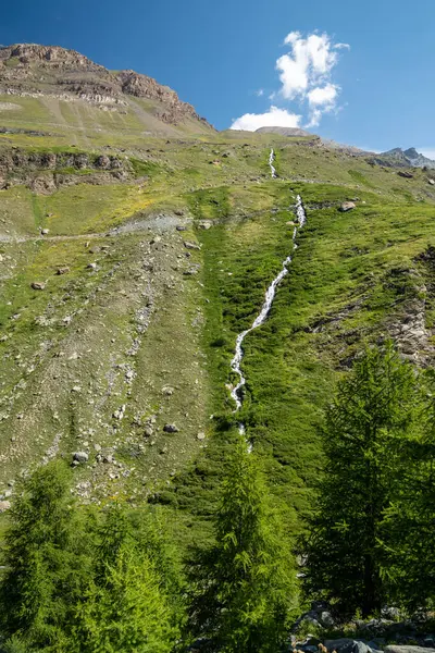 İsviçre 'nin Zermatt kentindeki Five Lakes Trail Yürüyüşü' nden bir dağ yamacından aşağı akan uzak şelale görülüyor.