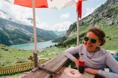 Kandersteg, Switzerland - July 24, 2024: Woman hiker relaxes at a hut while hiking along the Oeschinensee Lake hike in Switzerland clipart