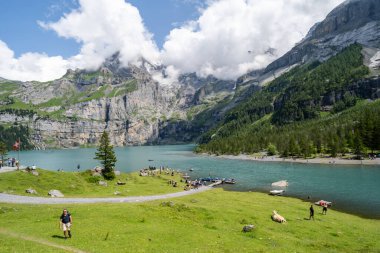 Kandersteg, İsviçre - 24 Temmuz 2024: Ziyaretçiler Oeschinensee Gölü kıyılarında güzel bir yaz gününün tadını çıkarıyorlar