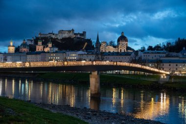 Geceleri Salzburg Avusturya - Makartsteg 'in (Makart Köprüsü) çitlerine asma kilit takan çiftler, Salzach Nehri' nin kıyısındaki Noel ışıklarıyla geceleri aydınlatılıyor.