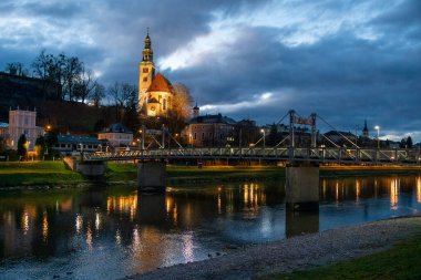 Night view of Our Lady of the Assumption church, Kirche Maria Himmelfahrt, on the foothills of the Monchsberg in Salzburg, Austria, along Salzach River clipart