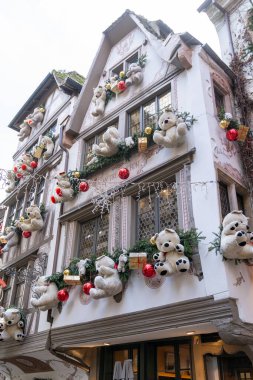 Strasbourg, Fransa - 6 Aralık 2024: Oyuncak ayılar, süsler ve Noel için şenlikli yeşillik ile süslenmiş beyaz bina. Strasbourg, Fransa Alscae bölgesi