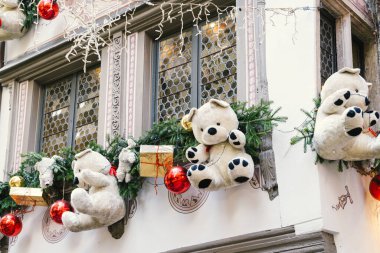 Oyuncak ayılar, süsler ve Noel için şenlikli yeşilliklerle süslenmiş beyaz bir bina. Strasbourg, Fransa Alscae bölgesi