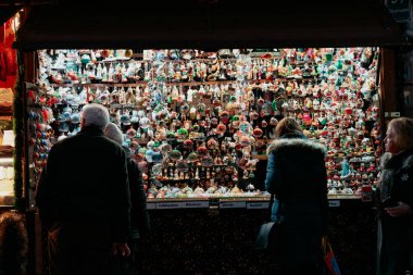 Munich, Germany - December 3, 2024: Customers shop at a booth selling Christmas ornaments during a Christmas market in evening clipart