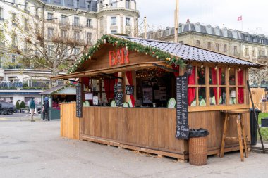 Cenevre, İsviçre - 10 Aralık 2024: Cenevre Gölü yakınlarındaki küçük Noel pazarında tezgah ve tezgahlar gıda ve ıvır zıvır satıyor