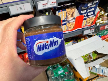 Basel, İsviçre - 9 Aralık 2024: Bir Lidl marketinde serpiştirilmiş bir kavanoz samanyolu fındık ezmesi tutuyor