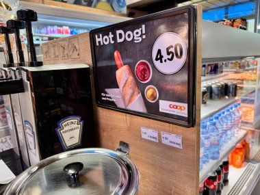 Basel, İsviçre - 9 Aralık 2024: Bir Coop marketinde satış için sosisli ve sıcak yiyecek reklamı yapın