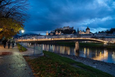 Geceleri Salzburg Avusturya - Makartsteg 'in (Makart Köprüsü) çitlerine asma kilit takan çiftler, Salzach Nehri' nin kıyısındaki Noel ışıklarıyla geceleri aydınlatılıyor.