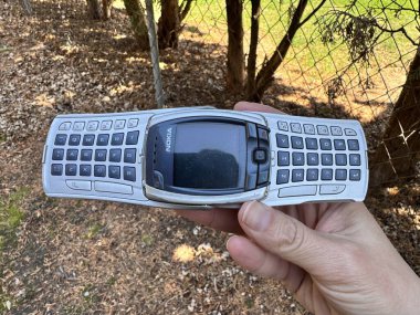 Minneapolis, Minnesota - 27 Nisan 2025: Hand, uzatılmış klavyeli klasik bir Nokia 6800 kapaklı telefon tutuyor. Telefon 2003 'ten.