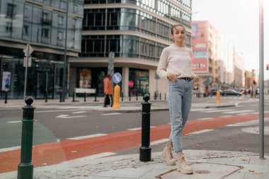 Süveter giyen havalı kız başka tarafa bakıyor. Dışarıda gezen şık bir kadının hayat tarzı portresi. Varşova 'da sokakta duran süveterli genç bir kadının hayat tarzı portresi..