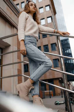 Profesyonel kadın işçiler açık havada duran teraslı takım elbise giyer. Parmaklıklara yaslanmış büyük bir gülümsemeyle modern ofis gökdeleninin keyfini çıkarırlar..