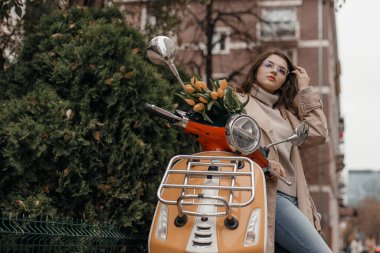 Genç, güzel hippi kız motosiklet şehir sokağında, sonbahar Avrupa tatili, seyahat, romantizm, gülümseme, mutluluk, eğlenme. Çiçekli kız scooter.