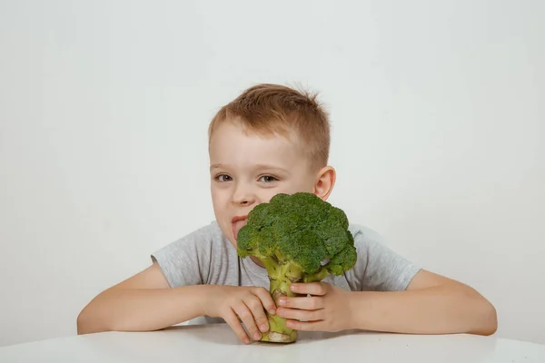 stock image The concept of healthy baby food. Handsome young teen boy holds fresh green broccoli in his hands. Healthy food concept.