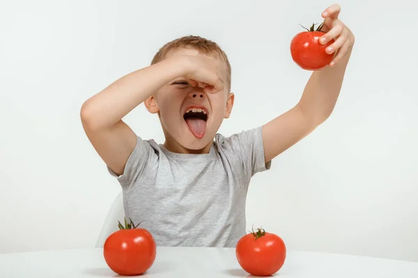 The boy don't like tomato. Nutrition and healthy eating habits for kids concept. Children do not like to eat red tomatoes. Little cute kid, boy refuse to eat healthy vegetables.