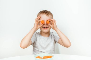Küçük çocuk havucu ısırıyor, bembeyaz. Öğrenme kavramı, iyi bir vizyon. Gözlerinin önünde havuç parçaları tutan çocuğun yakın portresi..