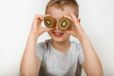 Stüdyo gri arka planda eğlenen bir çocuk. Kivisi olan tatlı bir çocuk..