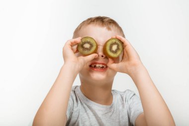 Stüdyo gri arka planda eğlenen bir çocuk. Kivisi olan tatlı bir çocuk..