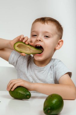 Sağlıklı gıda ve vejetaryenlik. Avokado ve Başparmak Yakından İzole Edildi. Avokado Yarısı Kesildi. Hafif arka planda taze avokadosu olan küçük bir çocuk. Yüksek kalite fotoğraf.