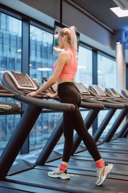 Koşu pistindeki iki çekici spor kadınının yan görünüşü. Çekici genç sporcu kadın spor salonunda çalışıyor. Koşu bandında koşuyor.