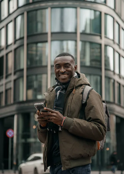 Stock image Young african american using smartphone at the city. Happy african american man using mobile phone on city street. Walking outdoors, using mobile phone. Looking looking for directions in navigator.