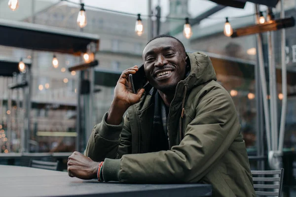 Business african american man wear on suit and sitting at office and speaking on phone. Man talking on cell phone in restaurant. Portrait of smiling man talking on cell phone while sitting.
