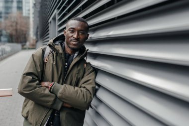 Gri duvara dayanmış bir adamın portresi. Gri duvara gülümseyen Afrikalı bir adamın portresi. Gülümseyen genç Afrikalı Amerikalı adam.