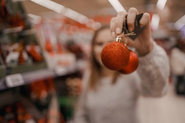 Xmas mağazasında yapay Noel ağacı seçen sevimli genç bir kadın. Noel konsept mağazasında inanılmaz Avrupalı. Bir kadın mağazadan yılbaşı ağacı için süslemeler alıyor..