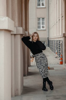 Eski şehirde, sıcak bir sonbahar gününde kemer yolunda poz veren güzel bir kız. Güzel binanın dışında sarışın bir kadın. Eski binalar ve duvarlar. Kemer ve sütunlu koridor.