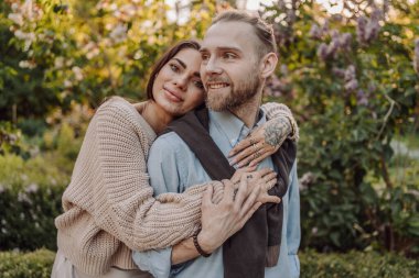 Gülümseyen dövmeli kız parkta erkek arkadaşına sarılıyor. Dövmeleri olan kızıl saçlı güzel bir kadın ve yürüyüşe çıkmış bir adam. Güzel, modaya uygun, şehir kıyafetleri içinde iki aşık sokakta öpüşüyor..