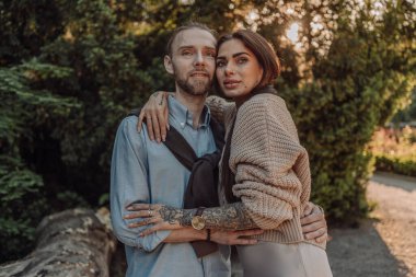 Gülümseyen dövmeli kız parkta erkek arkadaşına sarılıyor. Dövmeleri olan kızıl saçlı güzel bir kadın ve yürüyüşe çıkmış bir adam. Güzel, modaya uygun, şehir kıyafetleri içinde iki aşık sokakta öpüşüyor..