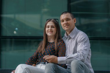 Genç aşıklar merdivenlerde oturup sohbet ediyorlar. Gülümseyen güzel kadın ve yakışıklı erkek arkadaşı. Gündelik yaz kıyafetleri içinde bir çift. Mutlu, neşeli bir aile. Merdivenlerde otur. Seyahat.