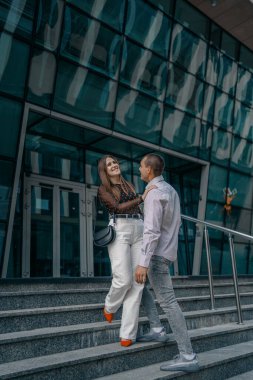 Genç aşıklar merdivenlerde oturup sohbet ediyorlar. Gülümseyen güzel kadın ve yakışıklı erkek arkadaşı. Gündelik yaz kıyafetleri içinde bir çift. Mutlu, neşeli bir aile. Merdivenlerde otur. Seyahat.