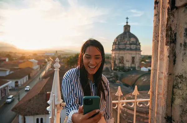 Şen şakrak bir kadın cep telefonu ve mesajları şehir bakış açısıyla kullanıyor..