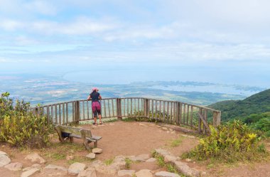 Bir ziyaretçi Mombacho bakış açısında duruyor, aşağıdaki geniş manzaranın tadını çıkarıyor.