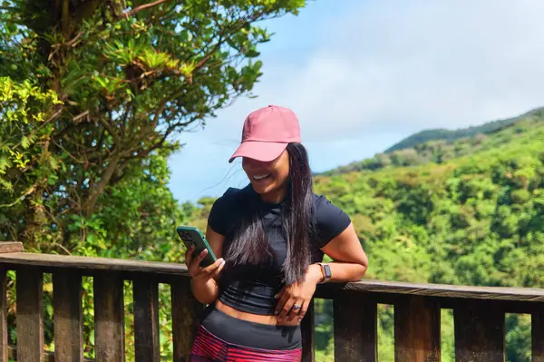 Mombacho Volkanı Doğa Koruma Alanı 'nda akıllı telefon kullanan gülümseyen Latin bir kadın.