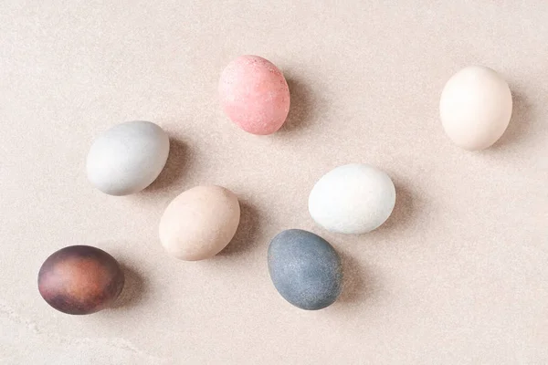 Natural dyed Easter eggs on beige table. Eco, pastel pale colors.