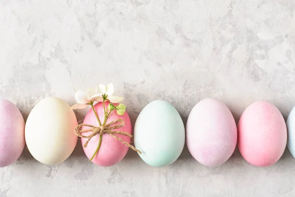 Pastel colored Easter eggs and spring flowers. Easter background, pastel pale colors. Copy space, top view.