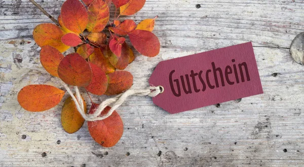 ドイツ語のテキストとラベル ギフトカードと秋の葉を持つ枝は木の板の上にあります — ストック写真