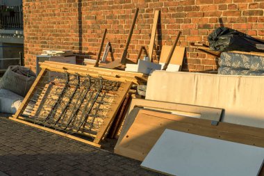 Yol kenarındaki yatak, yatak çerçevesi, masa ve dolaplı büyük çöp yığını.