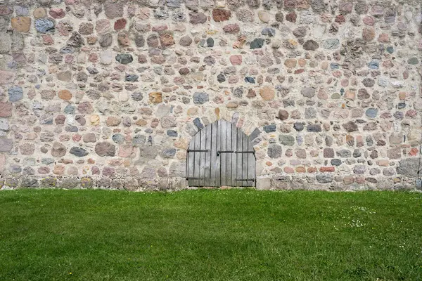 stock image Wall of a Romanesque church tower made of field stones with a wooden door