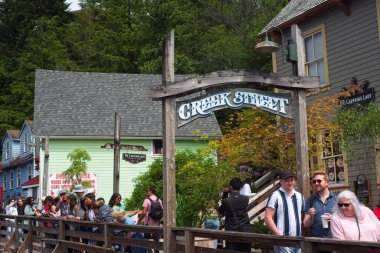 Ketchikan, AK, ABD - 27 Haziran 2024: Yolcu gemisi ziyaretçileri, bir zamanlar genelevlerin ve salonların bulunduğu ve büyük bir turistik ilgi odağı haline gelen Creek Caddesi 'ndeki sahil yolunda kuyruk oluşturdu.