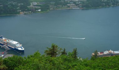 A small seaplane landing in the Gastineau Channel at Juneau, Alaska, with cruise ships docked nearby clipart